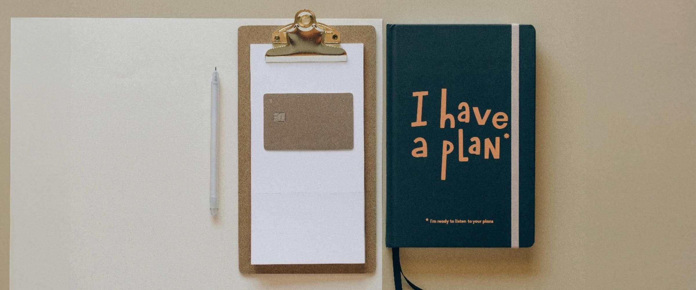 a pen and clipboard on top of a desk with a journal next to them that says, "I have a plan".